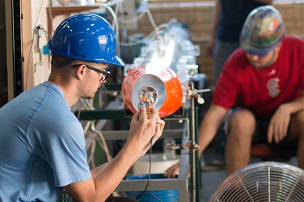 2 students in hardhats working in shop