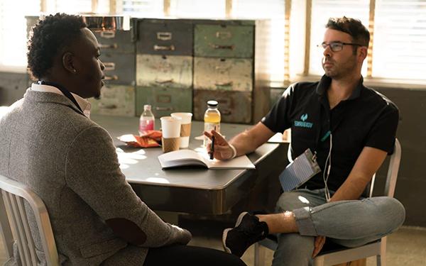 two men talking at desk